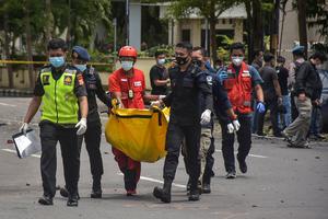 Indonesian police carry a bag with the remains of a suspected suicide bomber after an explosion outside a church in Makassar on March 28, 2021.