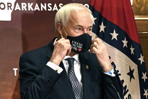 Arkansas Gov. Asa Hutchinson removes his mask before a briefing at the state capitol in Little Rock on July 20, 2020.