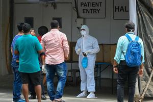 A health worker wearing Personal Protective Equipment (PPE) gear speaks with family members outside a recovery center to treat COVID-19  patients, in Mumbai, India, on April 22. Coronavirus infections are currently spiking there.