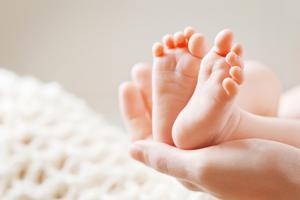 Mother holds baby's feet in the palm of her hands.