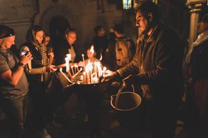 The faithful light candles in the Church of the Holy Sepulcher in Jerusalem. Prayer and action are needed in response to global religious persecution.