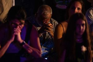 People pray during a community vigil on the beach for those missing after the collapse of the Champlain Towers South condominium building in Surfside, Florida, June 28. Catholic parishes are also holding prayer vigils.