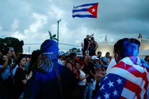 With some holding and waving Cuban and U.S. flags, demonstrators protest against the Cuban government July 11 in Miami. Thousands of Cubans across the island-nation took part in rare protests against the communist government, marching through several towns chanting, 'Down with the dictatorship,' and 'We want liberty.'