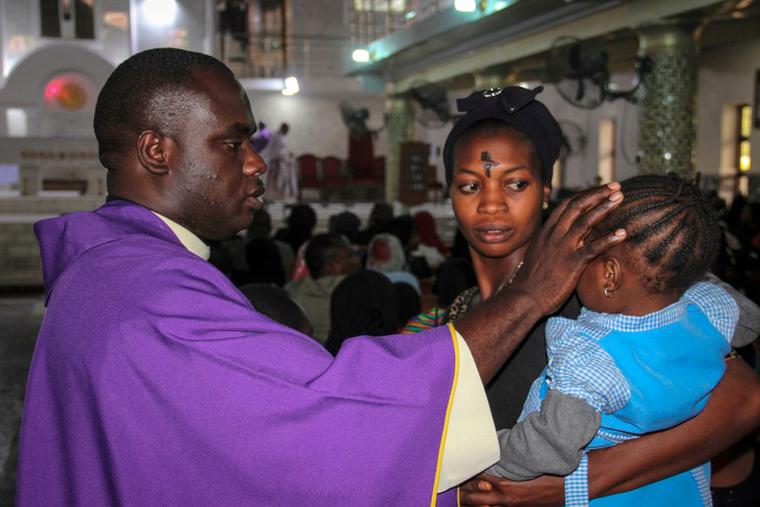 A priest signs the forehead of a child as catholics take part in the Ash Wednesday celebration at the St. Patrick cathedral in Maiduguri on February 26, 2020.