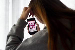 In this photo illustration, a woman looks at an abortion pill displayed on a smartphone on May 8, 2020, in Arlington, Virginia. The FDA temporarily lifted restrictions on the abortion pill in April due to the COVID pandemic prompting more widespread availability of chemical abortions.