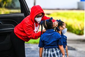 A mother adjusts the facemask of her child as she enters St. Lawrence Catholic School on the first day of school after summer vacation, north of Miami, on Aug. 18.