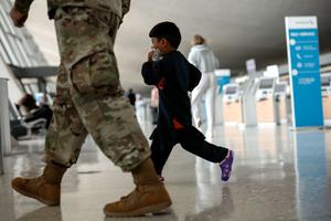 An Afghan boy walks with a U.S. service member as he and his family are led through the Dulles International Airport to board a bus that will take them to a refugee processing center after being evacuated from Kabul following the Taliban takeover of Afghanistan on August 31, 2021 in Dulles, Virginia.