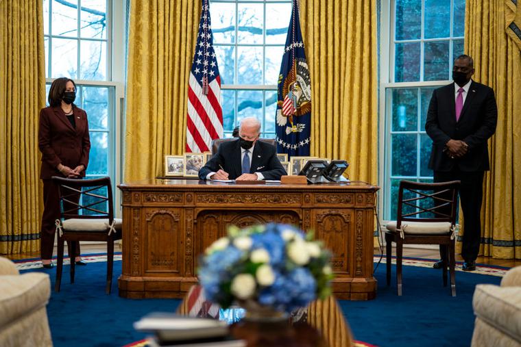 Flanked by Vice President Kamala Harris, l, and Secretary of Defense Lloyd Austin, r, U.S. President Joe Biden signs an executive order repealing the ban on transgender people serving openly in the military in the Oval Office of the White House on Jan. 25.