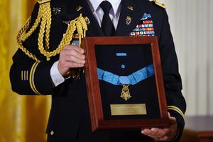 A U.S. Army officer holds the Medal of Honor for U.S. Army Chaplain (Captain) Emil J. Kapaun during an April 11, 2013, ceremony in the East Room of the White House in Washington, D.C. Father Kapuan received the medal posthumously for his service with the 3d Battalion, 8th Cavalry Regiment, 1st Cavalry Division, during combat operations against an armed enemy at Unsan, Korea.