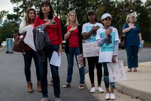Protesters and activists stand at attention as the national anthem is sung to open a Loudoun County Public Schools board meeting in Ashburn, Virginia, on Oct. 12. Loudoun County school-board meetings have become tense recently, with parents clashing with board members over issues such as the teaching of critical race theory and the response to in-school sexual-assault allegations. Directives from the U.S. attorney general have also angered parents of late.