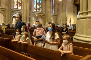 A family prays during St. Patrick's Cathedral Sunday first public Mass since March 2020 when pandemic stopped large gatherings