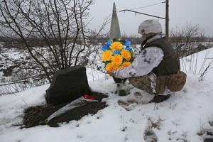 An Ukrainian servicemen lays flowers with the Ukrainian flag colors to the place where one of his friend was killed in 2017 on the frontline with the Russia-backed separatists near Avdiivka, Donetsk region, on February 2, 2022.