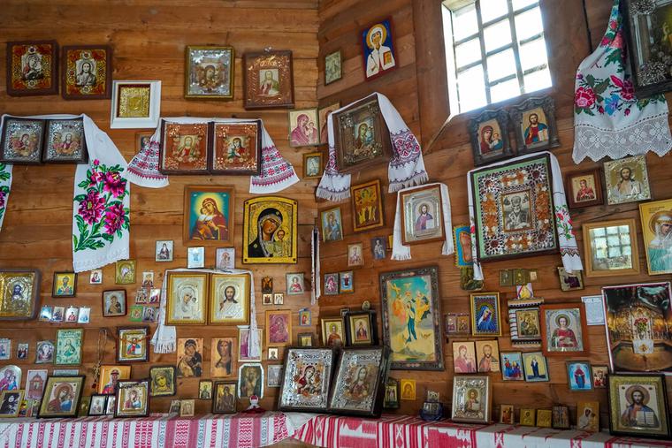 The interior wall of a Ukrainian chapel with different icons of the Virgin Mary displayed on the wall.