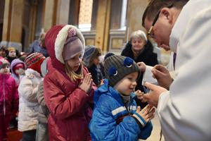 A priest marks the symbol of the cross with ash on the foreheads of Catholic children during an Ash Wednesday service on Feb. 26, 2020, in Fot, Hungary.