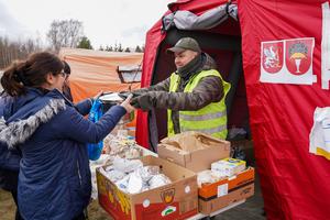 A Caritas volunteer assists Ukrainian refugees arriving at Przemyśl Główny train station in eastern Poland.