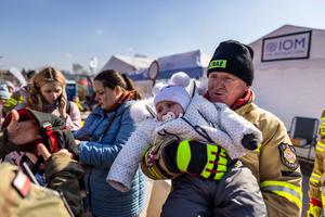 A polish fireman holds a baby at the Medyka border crossing on March 17, 2022. More than three million Ukrainians have fled across the border, mostly women and children, according to the UN.