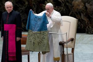 Pope Francis holds up a flag that he said was brought to him from ‘the martyred city’ of Bucha, Ukraine, during his general audience on April 6 at the Vatican.