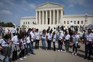 Students and parents from the Wickenberg Christian Academy, in Wickenberg, Arizona, pray in front of the U.S. Supreme Court Building in Washington May 3. In a leaked initial draft majority opinion obtained by Politico and authenticated by Chief Justice John Roberts, Justice Samuel Alito wrote that the cases Roe v. Wade and Planned Parenthood v. Casey should be overturned.