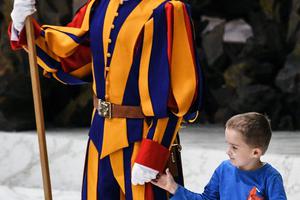 A boy who jumped from the audience takes a Swiss Guard's hand during Pope Francis’ weekly general audience on Nov. 28, 2018, in the Paul VI Audience Hall at the Vatican.