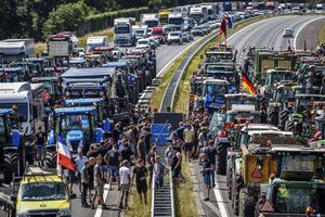 Farmers gather with their vehicles next to a Germany/Netherlands border sign during a protest on the A1 highway near Rijssen, Netherlands, June 29. They are protesting the Dutch Government's nitrogen plans, which would eliminate a sizable number of farms.