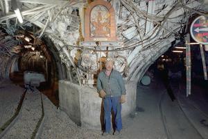 A coal miner poses under a statue of Saint Barbara, the patron saint of miners, in a mine gallery March 24, 1990, in Oignies, France.