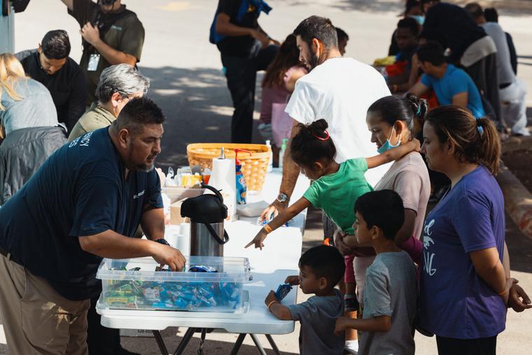 Groups of migrants receive food from the San Antonio Catholic Charities outside the Migrant Resource Center on September 19, 2022 in San Antonio, Texas. 