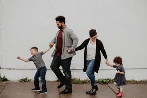 A family takes a walk together along the sidewalk. A family takes a walk together along the sidewalk.
