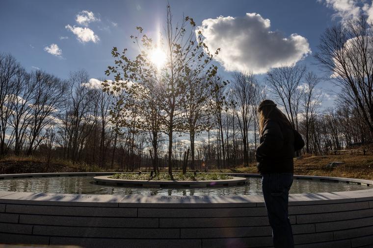 People visit the newly opened Sandy Hook Permanent Memorial  on Nov. 20 in Newtown, Connecticut. This December 14 marks the 10th anniversary of the Dec. 14, 2012, school shooting at Sandy Hook Elementary, where 26 people were shot and killed, including 20 6- and 7-year-olds and six adults. It was the deadliest elementary school shooting in U.S. history. At the memorial, water flows through a granite basin in a spiral inwards towards a center planter where a young tree symbolizes the age of the young victims, according to the designer’s website. 