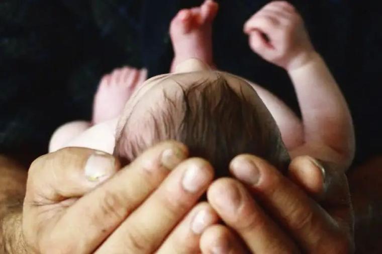 A baby in his father's hands. 