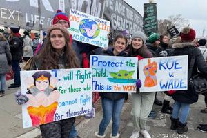Young adults hold colorful signs outside the U.S. Supreme Court at the March for Life in Washington, D.C., on Jan. 21, 2022.