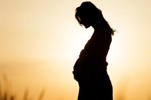 A pregnant woman outside at sunset A pregnant woman outside at sunset