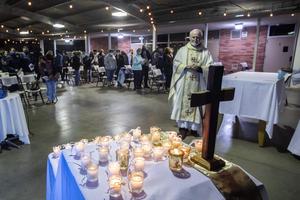 Bishop David O'Connell prays while he looks at candles placed on an altar representing people who lost their lives during the coronavirus pandemic, during a nondenominational memorial service at St. Cornelius Catholic Church in Long Beach, California, on Nov. 14, 2020. 