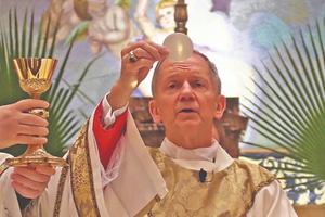 Bishop Thomas Paprocki consecrates the Host during Mass.