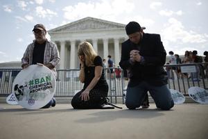 L-R: Rev. Pat Mahoney, Peggy Nienaber of Faith and Liberty and Mark Lee Dickson of Right to Life East Texas pray in front of the U.S. Supreme Court on April 21 in Washington. Organized by The Stanton Public Policy Center/Purple Sash Revolution, the small group of demonstrators called on the Supreme Court to affirm federal district-court Judge Matthew Kacsmaryk's ruling that suspends FDA approval of the abortion pill mifepristone.