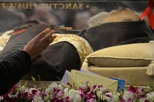 A woman touches the glass protecting the exhumed body of mystic saint Padre Pio in the Catholic church of San Lorenzo fuori le Mura (St Lawrence outside the walls) in Rome on February 4, 2016.
