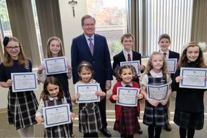 Students who are all winners of the St. Joseph art contest stand alongside Thomas Carroll, superintendent of schools for the Archdiocese of Boston.