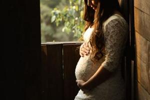 A pregnant woman contemplates the child within her womb. 