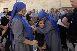 Nuns comfort a Palestinian woman as she mourns the death of a relative, killed in Israeli airstrikes that hit a church, during a funeral service in Gaza City, Friday, Oct. 20, 2023. 