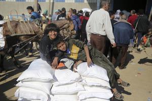 Palestinians are receiving bags of flour for humanitarian aid distribution in Bureij camp in the central Gaza Strip on November 30, 2023. Trucks carrying aid, which includes fuel, food, and medicine, are moving into Gaza through the Rafah crossing from Egypt since Nov. 24.
