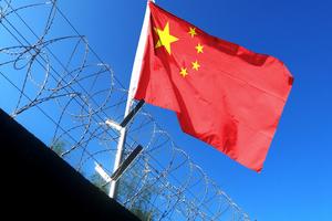 Chinese flag blows in the wind outside prison walls. 