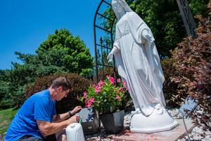 A man removes red spray paint from a statue of the Blessed Mother at the Church of the Ascension in Overland Park, Kansas.