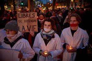 Protestors with cloths covering their mouths, hold candles and a slogan which reads " Free to defend life" during a silent pro-life demonstration in Paris, on February 28, 2024 as the Senate started debates for inclusion of abortion in the constitution.
