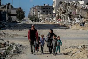 A Palestinian family walks past buildings destroyed in previous Israeli strikes in Gaza City on March 25, amid the ongoing conflict between Israel and Hamas.