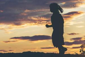 A young girl running as the sun sets. 