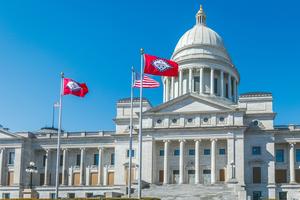 The Arkansas and American flags are in front of the Arkansas State Capitol Building in Little Rock, Ark.