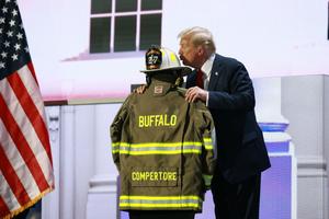 Republican presidential nominee, former U.S. President Donald Trump embraces the firefighter uniform of Corey Comperatore (the misspelling on the jacket was an error made years ago, according to the Buffalo Twp Vol Fire Co. Events Facebook page, which explained that ‘the spelling on his jacket was in error years ago and it was left that way by Corey. Corey did not change it and we will keep it as it was.’) as he speaks on stage on the fourth day of the Republican National Convention at the Fiserv Forum on July 18 in Milwaukee.