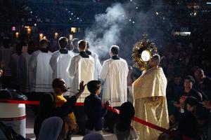 Benedictine Father Boniface Hicks, a spiritual director and retreat master, processes the massive golden monstrance containing the Eucharist into the midst of the assembled crowd in Lucas Oil Stadium.