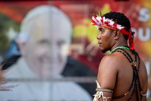 A man stands in front of a poster of Pope Francis outside APEC Haus in Port Moresby, Papua New Guinea, at the official welcome for the Pope, Sept. 7.
