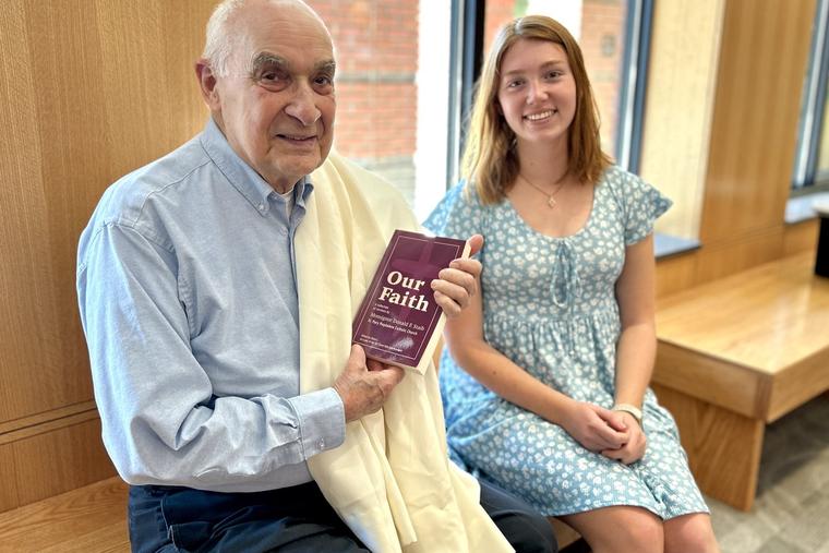 Msgr. Donald Staib receives a copy of the first printing of the ‘Our Faith’ volume, featuring 70 of his homilies, June 15 from Claire Curliss.