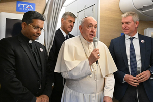 Pope Francis addresses journalists aboard the papal plane heading to Mongolia, with Cardinal-elect George Jacob Koovakad at left, on Aug. 31, 2023.